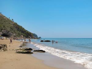 a beach with people swimming in the water at Apartment Costa di Kair ed Din-6 by Interhome in Sperlonga