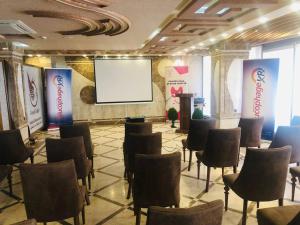 una sala de reuniones con sillas y una pantalla en un edificio en Royal Eagle Hotel en Nayaf