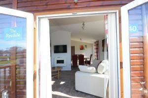 eine offene Tür zu einem Wohnzimmer mit einem Sofa in der Unterkunft Ryedale Lodge with Hot Tub in Malton