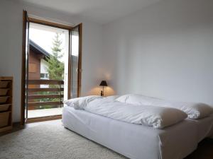 ein weißes Bett in einem Zimmer mit einem großen Fenster in der Unterkunft Apartment Galaxie 110 by Interhome in Verbier