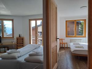 a bedroom with two beds and a desk and windows at Apartment Galaxie 110 by Interhome in Verbier