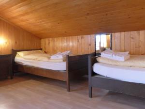 2 Betten in einem Zimmer mit Holzwänden in der Unterkunft Apartment Eigersonne by Interhome in Wengen