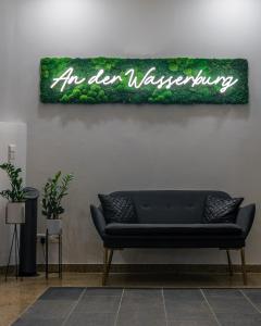 um sofá preto contra uma parede com um sinal que lê um vocabulário aberto em Hotel An der Wasserburg em Wolfsburg