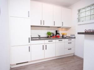 a white kitchen with white cabinets and a sink at Holiday Home Butzel by Interhome in Norddeich