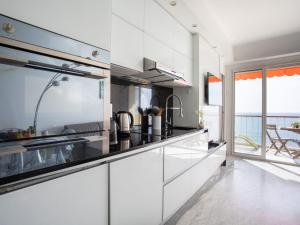 a kitchen with white cabinets and a view of the ocean at Apartment L'Angelina-1 by Interhome in Cros-de-Cagnes