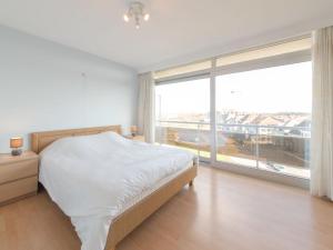 Un dormitorio con una cama y una ventana grande. en Apartment Ref 602 by Interhome, en Bredene