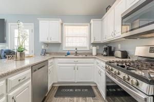 a kitchen with white cabinets and a stove top oven at Unwind in a Modern Riverdale Home in Riverdale