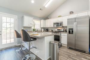a kitchen with white cabinets and a stainless steel refrigerator at Unwind in a Modern Riverdale Home in Riverdale