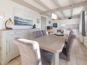 uma cozinha e sala de jantar com uma mesa de madeira e cadeiras em Holiday Home Noordzeepark Zeewind 2-1 by Interhome em Mispelburg