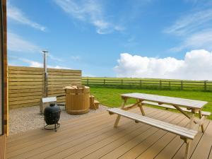 una terrazza in legno con panchina e cestino di Sun Rise a Penzance