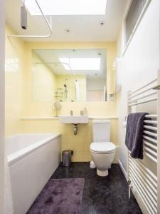 a bathroom with a tub and a toilet and a sink at Sunset Beach House By Air Premier in Seaford