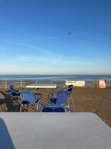 a table and chairs on a beach with the ocean at Happy Holiday apartments in Mablethorpe