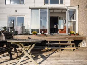 una terraza de madera con mesa y sillas frente a una casa en Sunset Beach House By Air Premier en Seaford