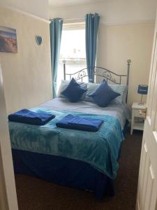 a bedroom with a bed with blue pillows and a window at Happy Holiday apartments in Mablethorpe