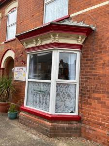 a window of a brick building with a curtain at Happy Holiday apartments in Mablethorpe