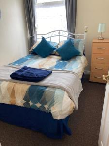 a bedroom with a bed with blue pillows and a window at Happy Holiday apartments in Mablethorpe
