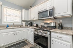 a kitchen with white cabinets and a stove and microwave at Unwind in a Modern Riverdale Home in Riverdale