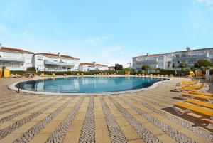 a large swimming pool with lounge chairs and buildings at Palmeiras Reais 110 in Portimão