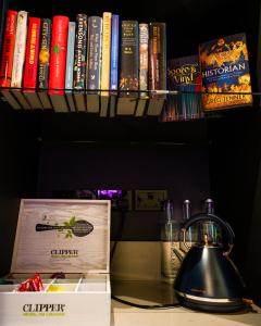 un estante con libros y una tetera sobre una mesa en The Wesley Camden Town, en Londres