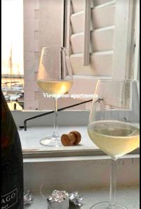 two glasses of white wine sitting on a window sill at ApartHouse Porto in Piran