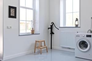 a white laundry room with a washing machine and a stool at Vakantieverblijf de Trommel in Domburg