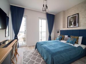1 dormitorio con cama azul y escritorio en Kasprzaka 29 Bliska Wola Tower By Perfect Apart, en Varsovia