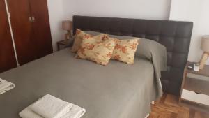 a bed with a gray headboard and pillows on it at Mi depto en Córdoba II . in Córdoba