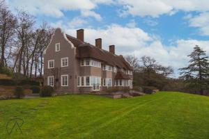 Luxury Rural Family Getaway with Tennis Court في Buckinghamshire: منزل كبير مع ساحة كبيرة مع عشب أخضر