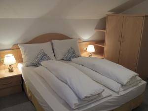 a bedroom with a bed with white pillows and two lamps at Residence Adler in Tesimo