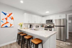 Una cocina con gabinetes blancos y un refrigerador de acero inoxidable. en Recently Renovated Clarksville Apt for 4 and Parking, en Austin