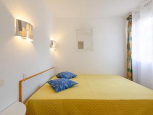 Cette petite chambre comprend un lit jaune avec des oreillers bleus. dans l'établissement Apartment Les Coteaux de la Nartelle-23 by Interhome, à Sainte-Maxime
