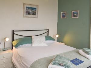 a bedroom with a bed and a night stand with two lamps at Spindrift in Coverack