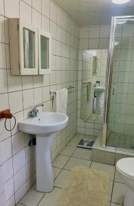 a white bathroom with a sink and a mirror at Timebridge Mansions in Johannesburg