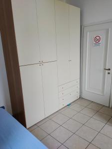 een slaapkamer met witte kasten en een witte tegelvloer bij B&B Villa Hope in Malnate