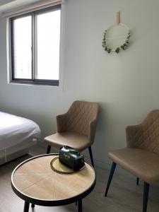 a room with two chairs and a table and a bed at 極旅inn in Taichung