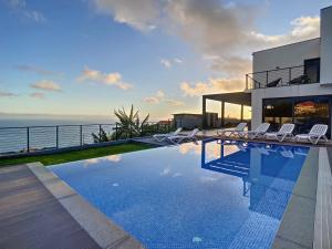 a house with a swimming pool with a view of the ocean at Villa de la Ponte by Atlantic Holiday in Arco da Calheta