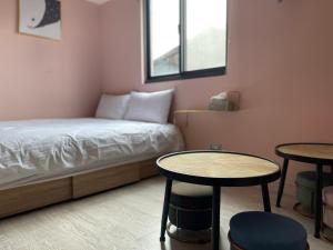 een kleine kamer met een bed en twee tafels bij 極旅inn in Taichung