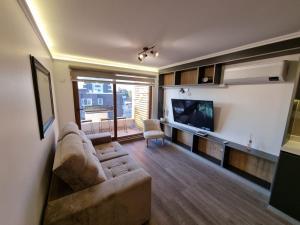 ein Wohnzimmer mit einem Sofa und einem TV in der Unterkunft Depto 2D+2B amoblado y equipado. in Los Ángeles