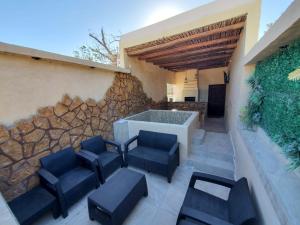 a patio with four blue chairs and a stone wall at La casita de Carmen con terraza in Cuatrociénegas de Carranza