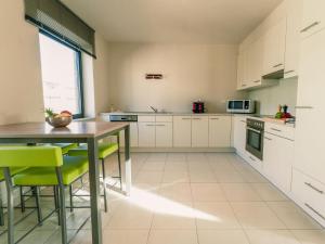 una cucina con armadi bianchi, tavolo e sedie di Apartment Rooftop Breeze by Interhome a Ostenda