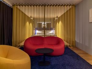 a living room with a red couch and a table at b'mine hotel Düsseldorf in Düsseldorf