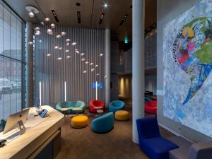 a lobby with colorful chairs and a large mural at b'mine hotel Düsseldorf in Düsseldorf
