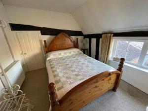 een slaapkamer met een houten bed en een raam bij The Bridge Street Historic Guest House in Sudbury