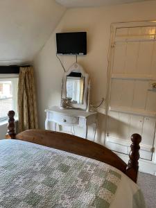 a bedroom with a bed and a mirror and a television at The Bridge Street Historic Guest House in Sudbury
