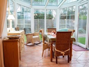 einen Wintergarten mit einem Tisch, Stühlen und Fenstern in der Unterkunft Holiday Home Bärbel by Interhome in Norden