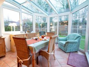 a conservatory with a table and chairs and windows at Holiday Home Bärbel by Interhome in Norden