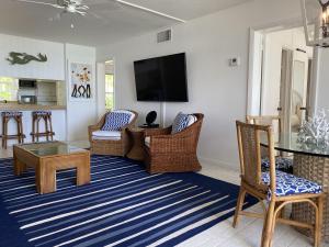 sala de estar con sillas de mimbre y TV de pantalla plana en Treasured villa, en Savannah Sound