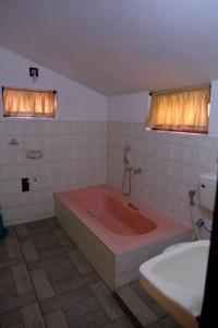 La salle de bains est pourvue d'une baignoire rouge et d'un lavabo. dans l'établissement The Wayanad Club, à Sultan Bathery
