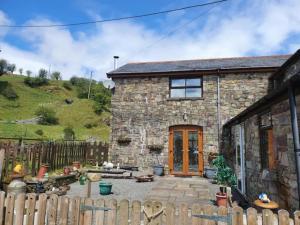 a stone house with a fence in front of it at Cwm Farm Cwtch in Merthyr Tydfil