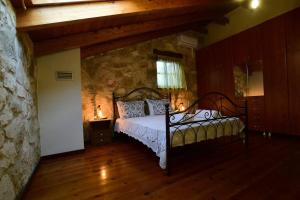 a bedroom with a bed and a stone wall at Kidóni Villas in Gaïtánion